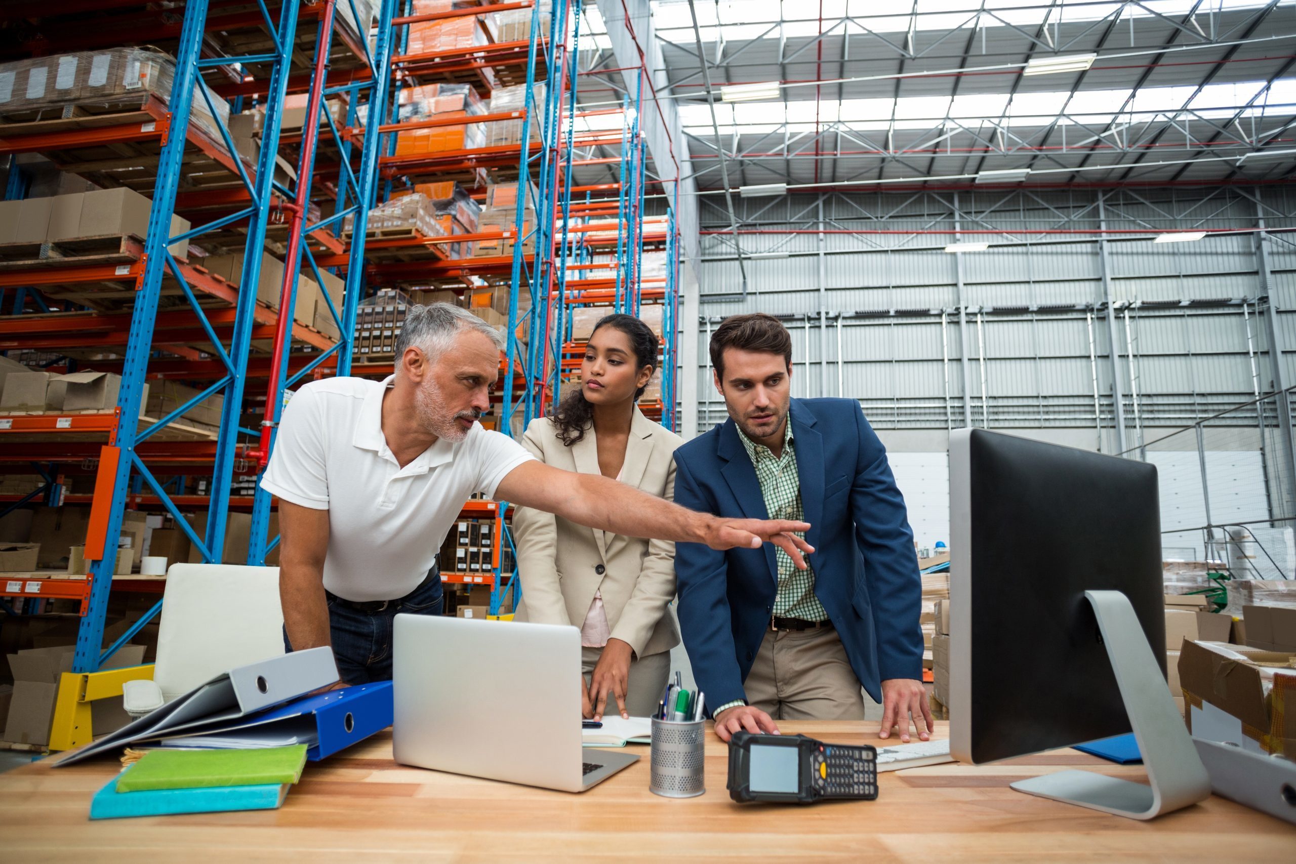 Warehouse manager and worker reviewing supplies using a computer in a distribution centre