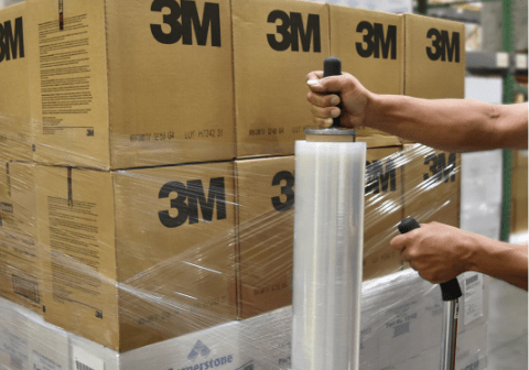 wrapping_pallet Worker hand wrapping a pallet with stretch film in a warehouse